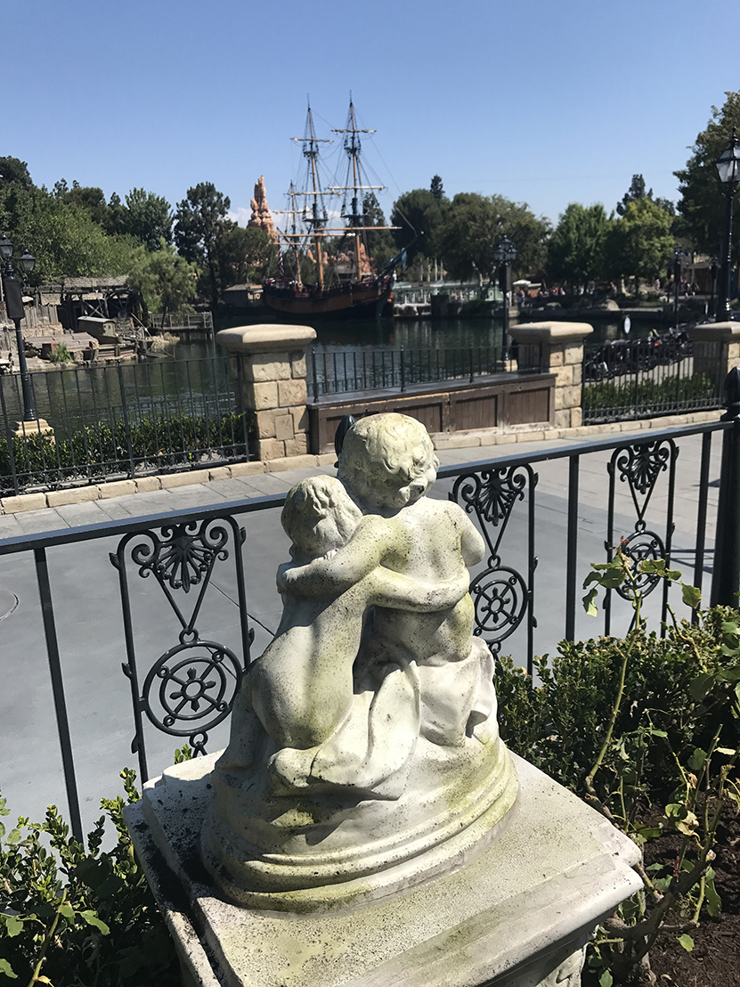Statue of two cherubs hugging and looking over the Rivers of America in Disneyland's New Orleans Square
